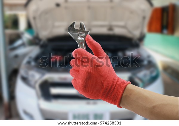 Car repairing,Hand of car technician auto mechanic\
with a wrench working in garage. service in auto repair\
station.vintage tone,for\
banner
