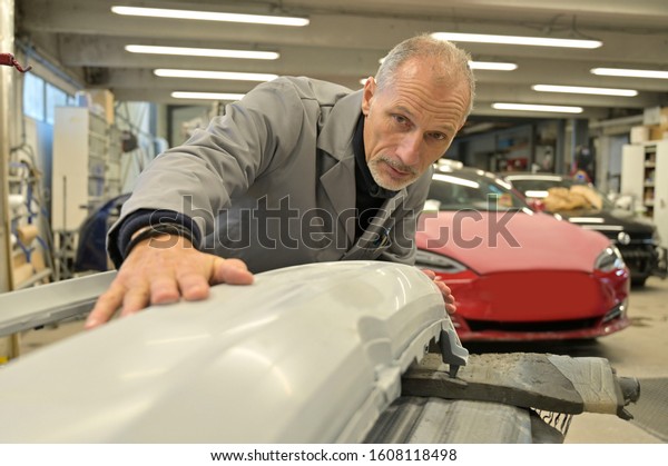 Car repairman\
checking body shell\
painting