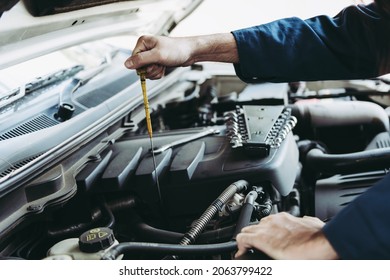Car Repairman is Checking Engine Oil Level in Automotive Workshop, Maintenance Car Worker Inspection Checkup Oil Vehicle Engines by Dipstick Test at Automobile Shop Station. Auto Car Services