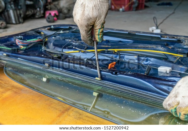 Car repairman near the disassembled car door and\
fiddling with the wires from the alarm. The concept of repair of\
the wiring of car door