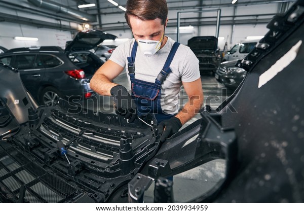 Car repairman\
reaching inside a car with\
wrench