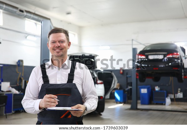 Car repairman standing workshop with folder hands.\
Checking original mileage car. Inspection cabin and internal\
equipment. Visiting workshop providing quality services. Carry out\
some locksmith work
