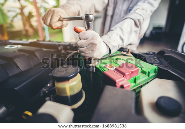 Car repairman
wearing a white uniform standing and holding a wrench that is an
essential tool for a
mechanic