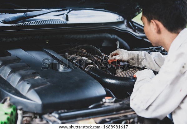 Car repairman\
wearing a white uniform standing and holding a wrench that is an\
essential tool for a\
mechanic