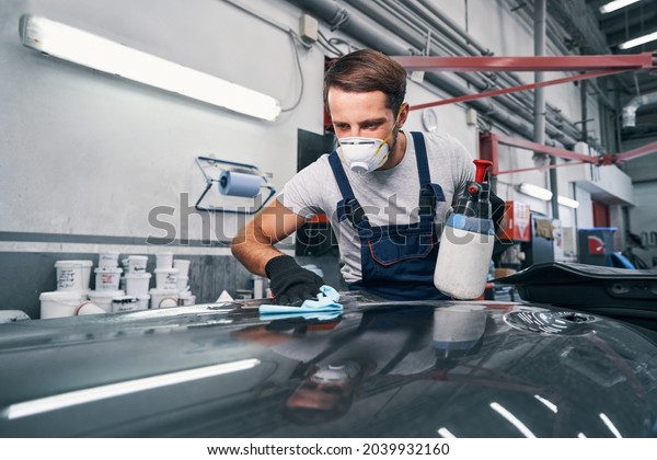 Car repairman\
wiping car surface with\
cloth