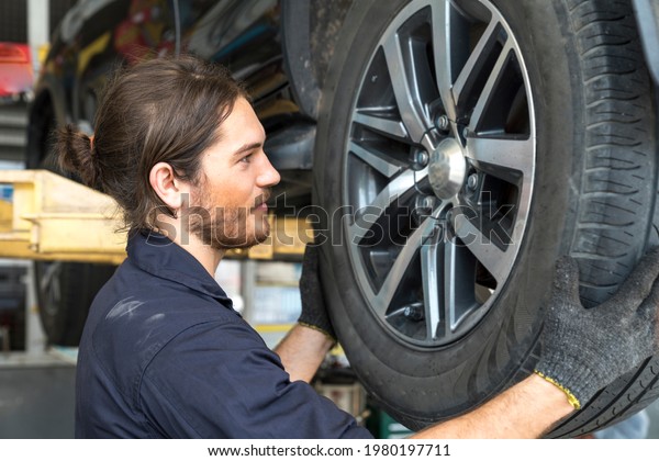 Car\
repairs. Auto services and Small business concepts. The car service\
mechanic is replacing the wheels. Removing the\
wheel.