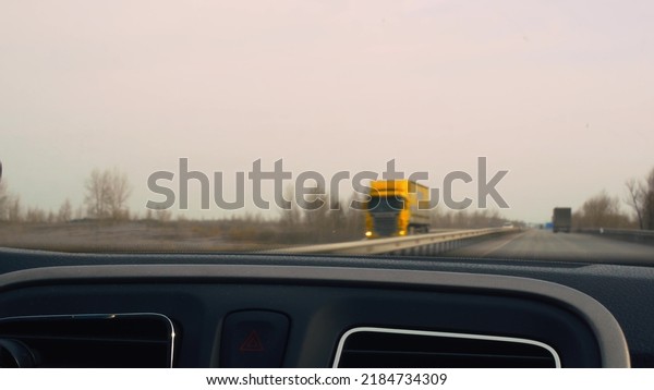 A car ride along the highway, the view from the\
car interior to the windshield while driving at high speed towards\
the flow of trucks and other cars in blur. Video from the\
windshield in motion.