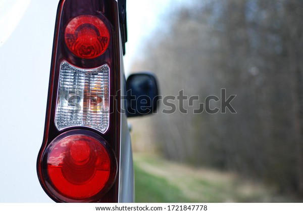 Car rides on the highway. Back view . Against the\
background of spring forest, road, flowers on the lawn, taillights,\
car mirror.
