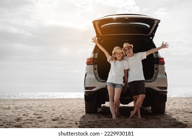 Car road trip travel of couple enjoying beach relaxing on hood of sports utility car. Happy Asian woman, man friends smiling together on vacation weekend holidays on the beach. - Powered by Shutterstock