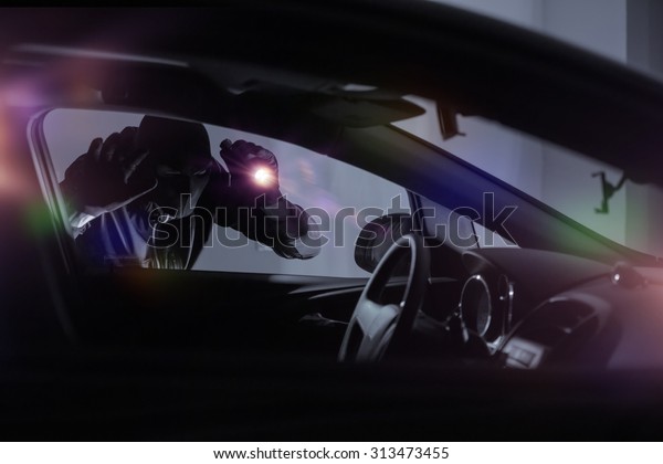 Car Robber with Flashlight Looking Inside the Car.\
Car Security Theme.