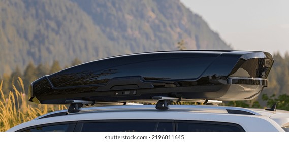 Car With The Roof Rack With Cargo Box. Black Plastic Car Rooftop Cargo Box Or Roof Carrier For Traveling. Removable Storage Container Mounted On Car Roof Rack. Beautiful Nature Background