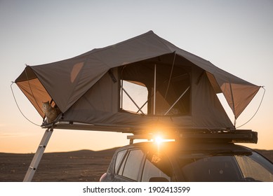 A Car Rooftop Tent For Camping On The Roof Rack Of An Off-road Car In A Desert At Sunset