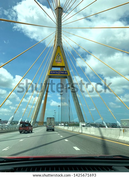The car is running on a bridge with a\
blue sky background and white clouds in the clear sky atmosphere at\
Bhumibol 2 Bridge Bangkok Thailand, June\
2019