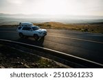 Car running on high altitude mountain top trail in the sunrise