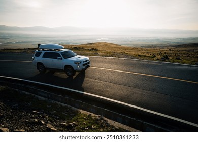 Car running on high altitude mountain top trail in the sunrise