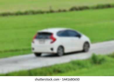 Car running on the road between the sides of rice field