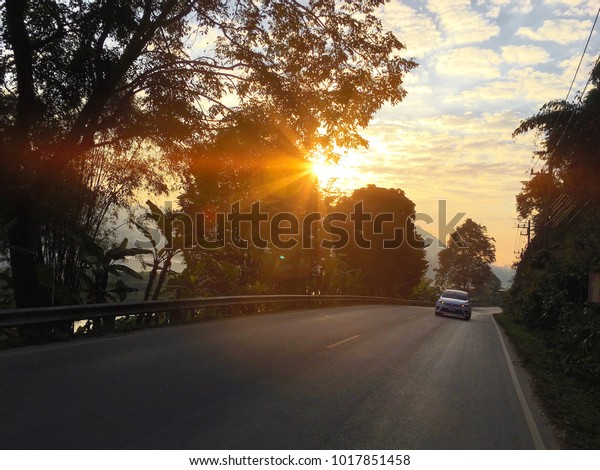 A car running on\
the road in the morning in Nong Khai Province, Thailand. Photo\
taken in January 2018