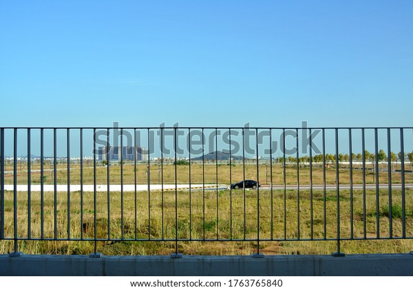 The car runs\
in a field overlooking the\
fence.