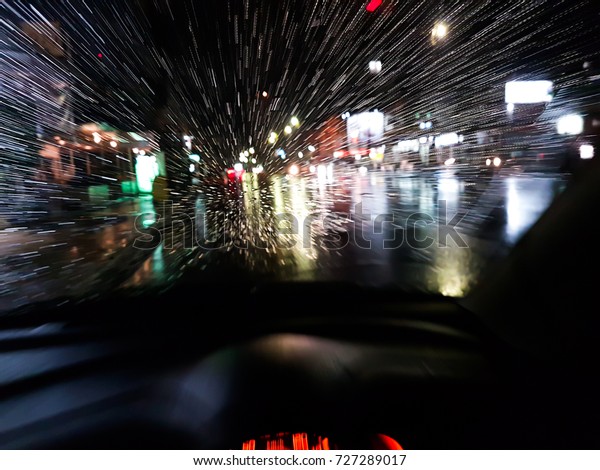 The car rushed in\
the rain.Scene view from car windshield at vehicles moving as\
streaks of light at night 