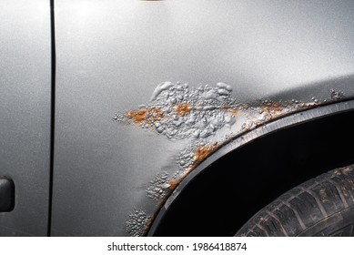 Car rust and corroded paint. Metal corrosion, cracked paint, holes in the car fender close-up. Part of an automobile body in metallic gray