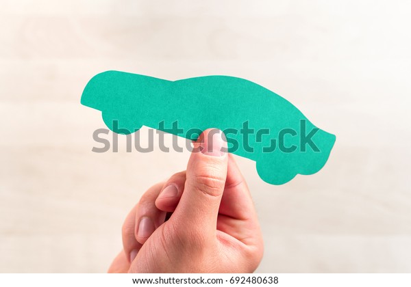 Car sale or loan, auto insurance,\
driving school or vehicle inspection and check up concept. Buying\
new or used automobile. Hand holding a cardboard paper\
shape.
