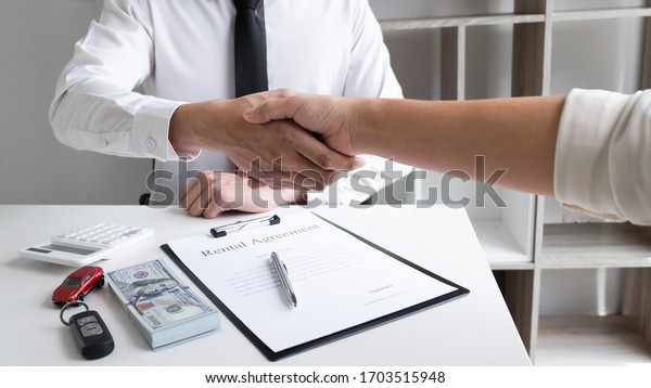 Car
sales agent and client shaking hand after finishing signed the car
rental agreement in the office, Car rental
concept.