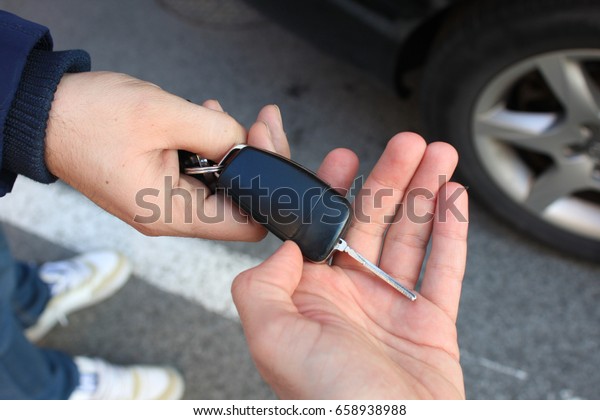 car sales. one person sells car and gives the key
to the new owner