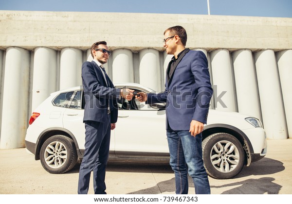 car sales. one person sells car and gives the key
to the new owner