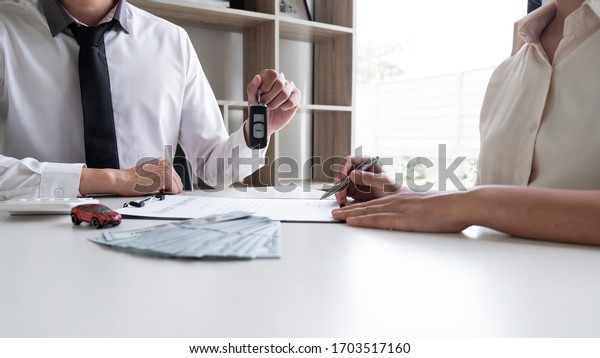 Car\
sales representative gives the key to customer after signed the\
sale contract in the office, Car rental\
concept.