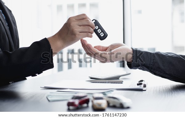 Car sales
representative or sales manager submits a car key to a client who
has approved financial loans with the company, Approval of
financial and banking loans
concept.