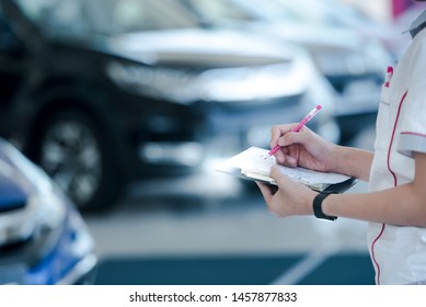 Car Sales Staff Are Writing Car Records In Stock In The Sales Representative Showroom., Taking Notes On New Cars In Stock., Taking Notes