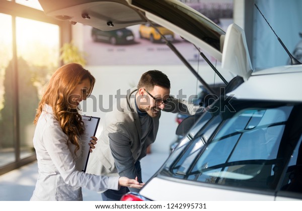 Car salesman and customer testing new\
car at vehicle dealership. Good customer\
service.