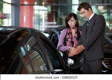 Car Salesman Explaining Car Features To Customer