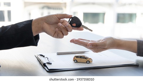 Car salesman gave the keys to the customers who signed the purchase contract legally, Successful completion of car sales, Purchase contract and key delivery. - Shutterstock ID 1937358310
