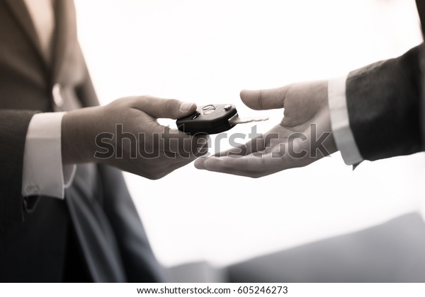 Car salesman handing over the keys for a new\
car to a young businessman