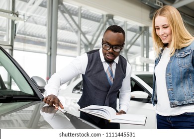 Car salesman helps client to choose a new car in the dealership - Powered by Shutterstock