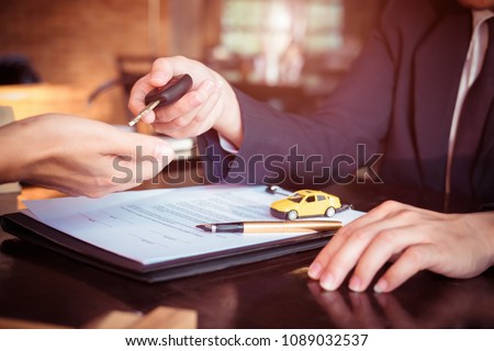 Car salesman holding key to his client after signing contract,concept for sale car,insurance with car, moving car or renting car
