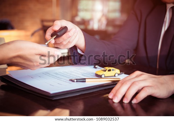 Car salesman holding key to his client after\
signing contract,concept for sale car,insurance with car, moving\
car or renting car\
