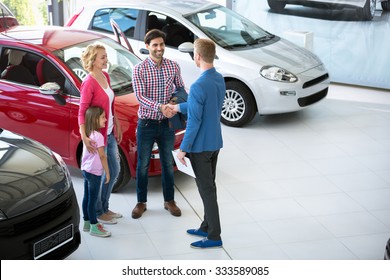 car salesman showing new vehicle to family customers