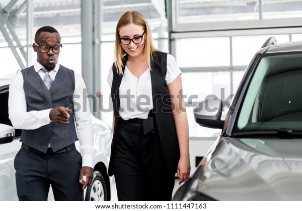 Car salesman shows the customer a surprised car\
in the showroom