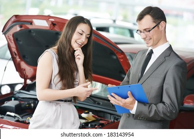 Car salesperson demonstrating new automobile to young woman