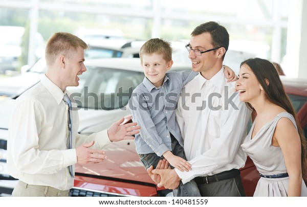 Car salesperson demonstrating new automobile to
young family with child