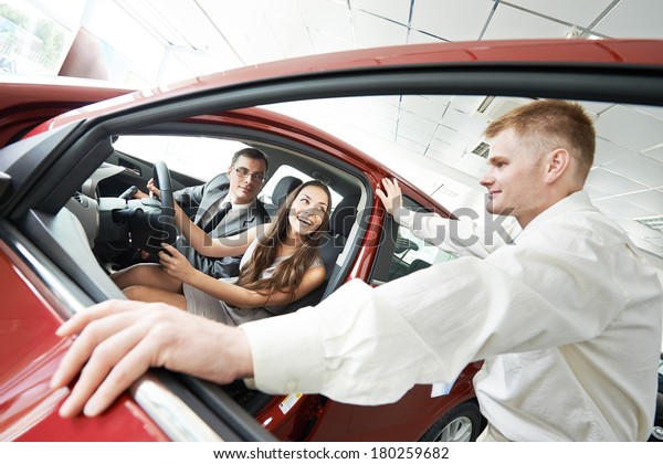 Car salesperson demonstrating new automobile to\
young woman
