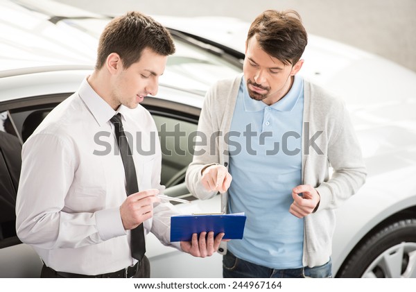 Car salesperson demonstrating a new automobile to\
young couple.