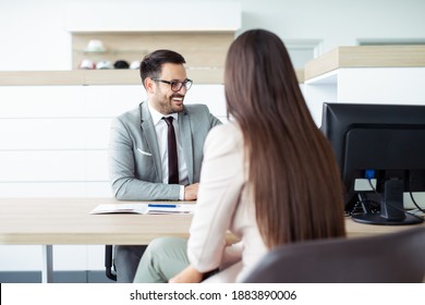 Car salesperson discussing with female customer while sitting in showroom.