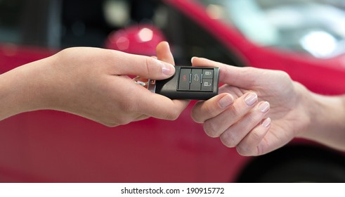 Car Saleswoman Handing Over The Keys For A New Car To A Young Woman