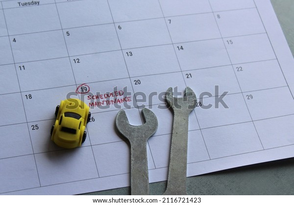 Car scheduled maintenance
concept. Toy car, spanner and calendar with text SCHEDULED
MAINTENANCE