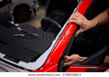 Car seal adjustment, Precision alignment of car door rubber seal at workshop, Detailed view of fitting and aligning vehicle door seal with lighting