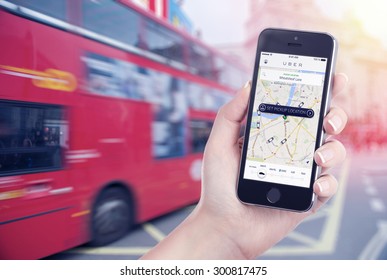 Car Search Through The Uber App That Is Displayed On The Apple IPhone Screen In Female Hand. Blurred Street View With Bus And Flare Sun Light On The Background. Varna, Bulgaria - May 26, 2015.