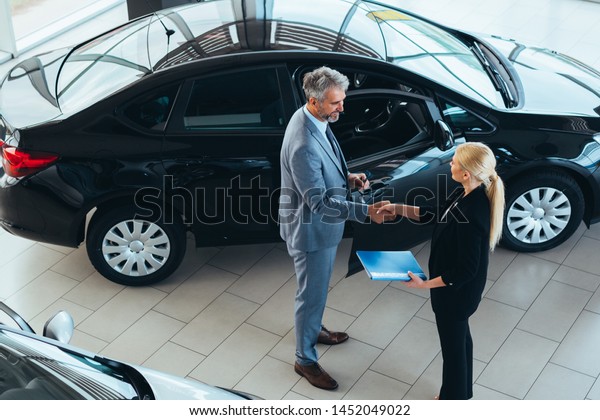 car sell\
agent handshake with client in car\
showroom